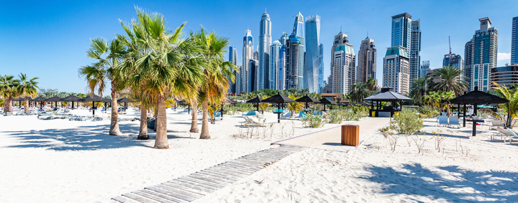 Ein Strand mit Palmen in Dubai mit der Skyline im Hintergrund